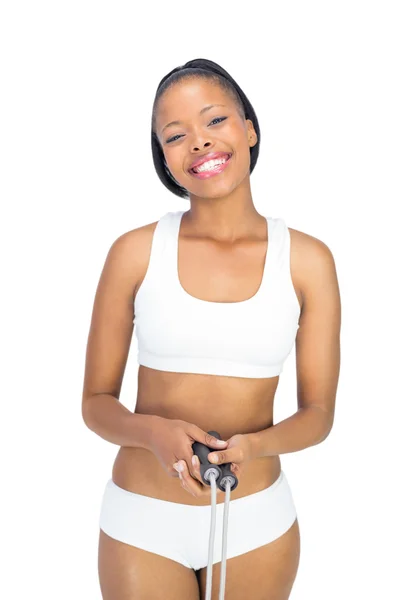 Счастливая женщина в спортивной одежде держит скакалку и улыбается в камеру — стоковое фото