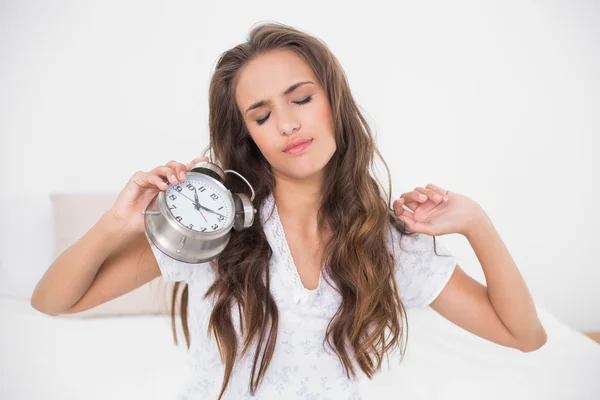 Morena cansada sosteniendo reloj despertador —  Fotos de Stock