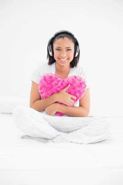 Spokojnej youngmodel przytulanie poduszkę i słuchania muzyki — Zdjęcie stockowe