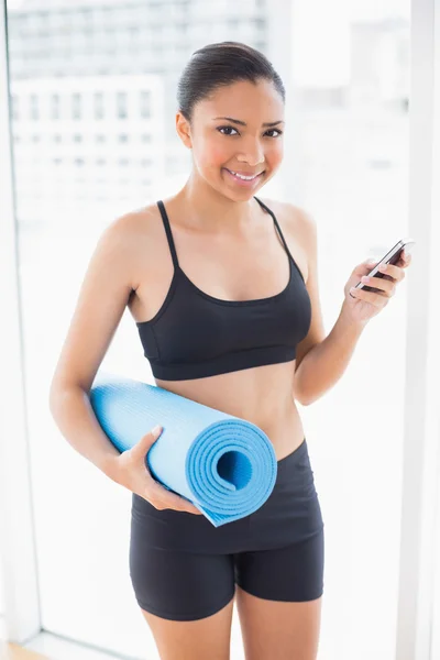 Fröhliches Model in Sportbekleidung mit Gymnastikmatte und Handy — Stockfoto