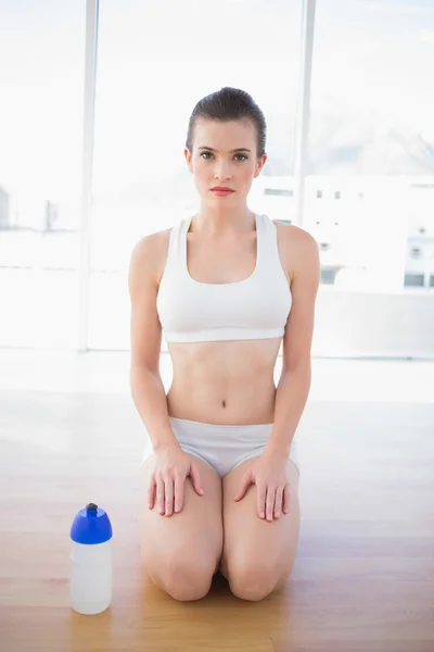 Stern fit model in sportswear kneeling on the floor — Stock Photo, Image