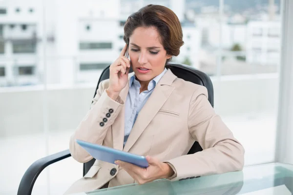 Serious businesswoman on a call holding tablet — Stock Photo, Image