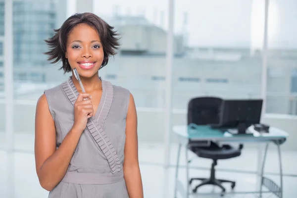 Smiling businesswoman standing in her office holding pen — Stock Photo, Image