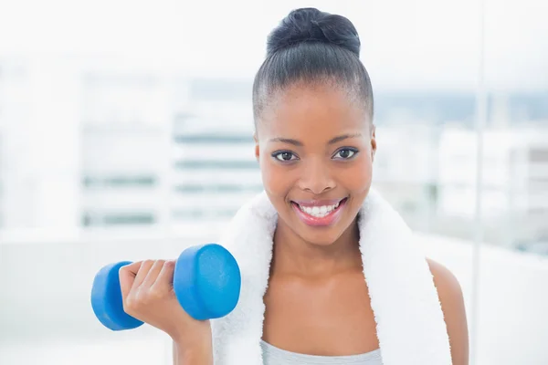 Smiling woman with towel around her neck working out with dumbbell — Stock Photo, Image