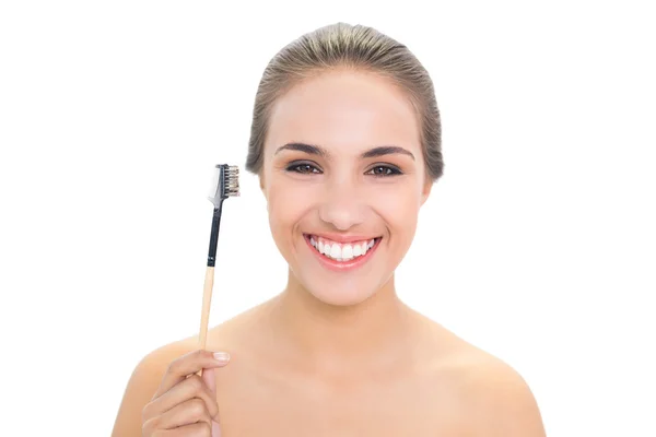 Mujer joven sonriente sosteniendo el cepillo de cejas —  Fotos de Stock