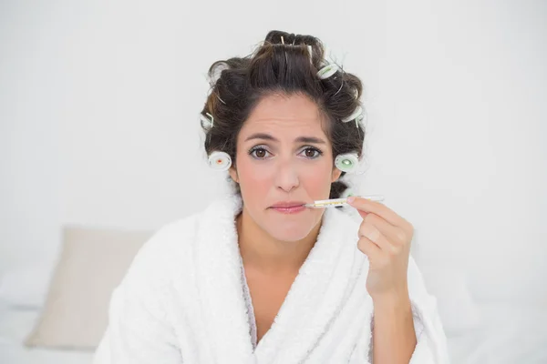 Sad natural brunette using thermometer — Stock Photo, Image