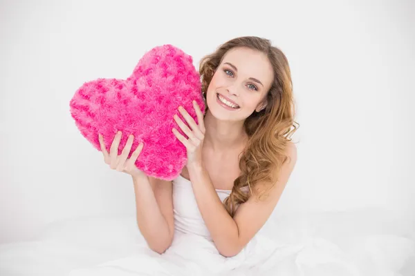 Happy attractive brunette holding heart pillow — Stock Photo, Image