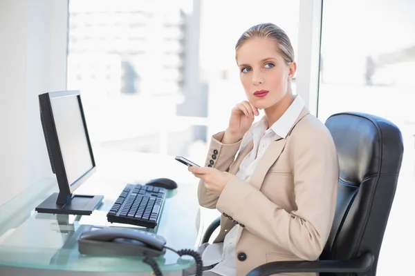 Thoughtful blonde businesswoman texting — Stock Photo, Image