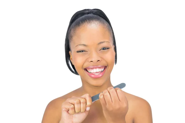 Cheerful woman using nail file while looking at camera — Stock Photo, Image