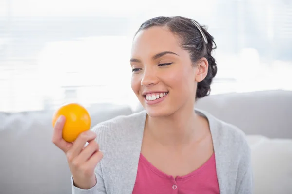 Счастливая женщина держит оранжевый и смотрит на него — стоковое фото
