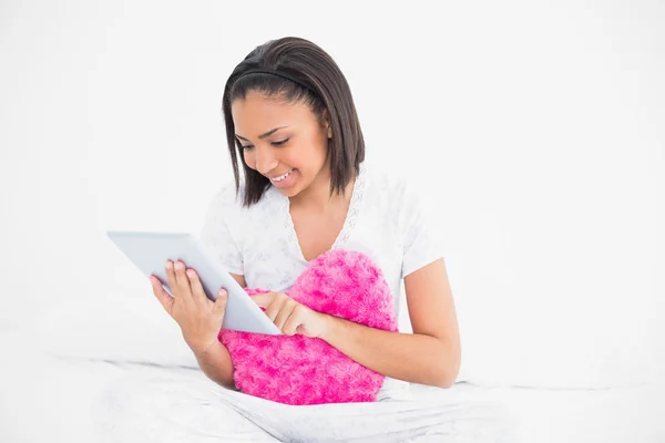 Skoncentrowany młody model gospodarstwa poduszkę i korzystania z komputera typu Tablet — Zdjęcie stockowe