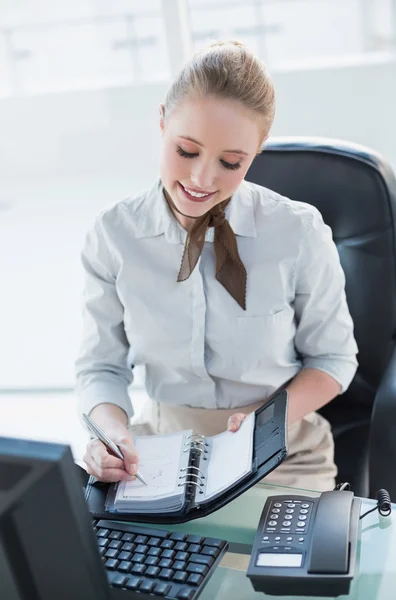 Blonde smiling businesswoman writing in diary — Stock Photo, Image