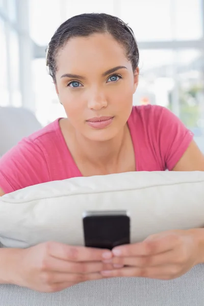 Femme sérieuse couchée sur le canapé et textos — Photo