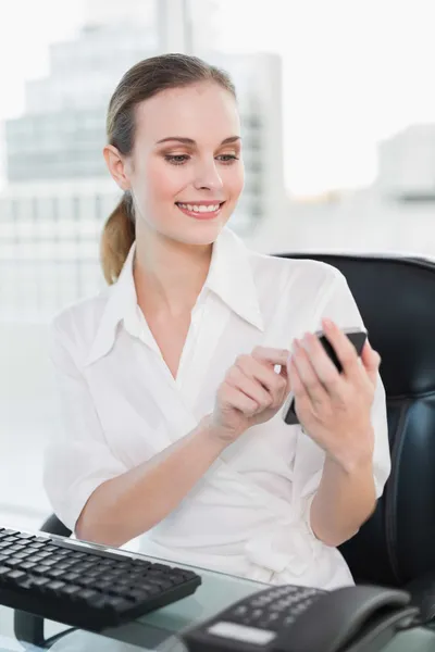 Zufriedene Geschäftsfrau sitzt am Schreibtisch und schickt einen Text — Stockfoto