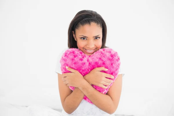 Delighted young model cuddling a heart-shaped pillow — Stock Photo, Image