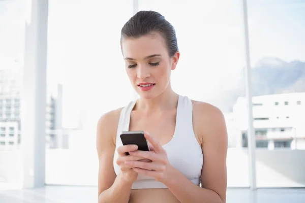 Koncentrerad fit modell i sportkläder med hennes mobiltelefon — Stockfoto