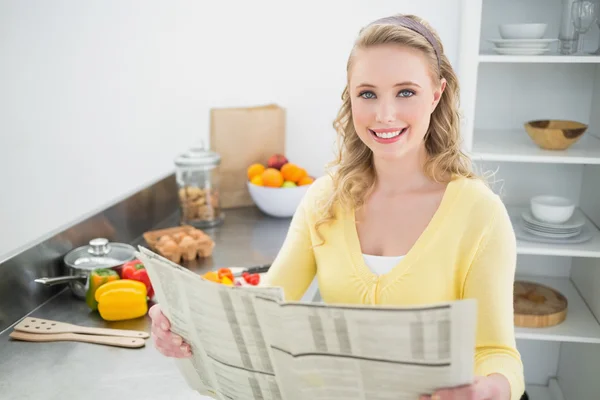 Lächelnde süße Blondine hält Zeitung in der Hand — Stockfoto