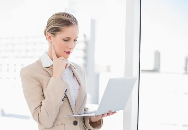 Pensativo mujer de negocios rubia utilizando el ordenador portátil —  Fotos de Stock