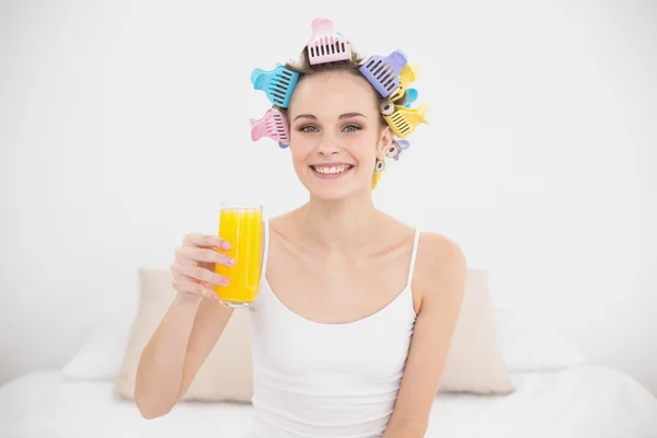 Bir bardak portakal suyu tutan saç curlers içinde büyüleyici kadın — Stok fotoğraf