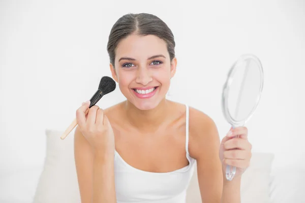 Model in white pajamas applying powder on her face — Stock Photo, Image