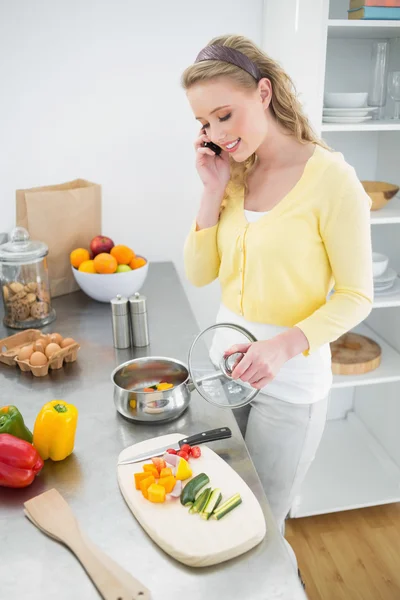 Contenido lindo teléfono rubio mientras se prepara una comida —  Fotos de Stock