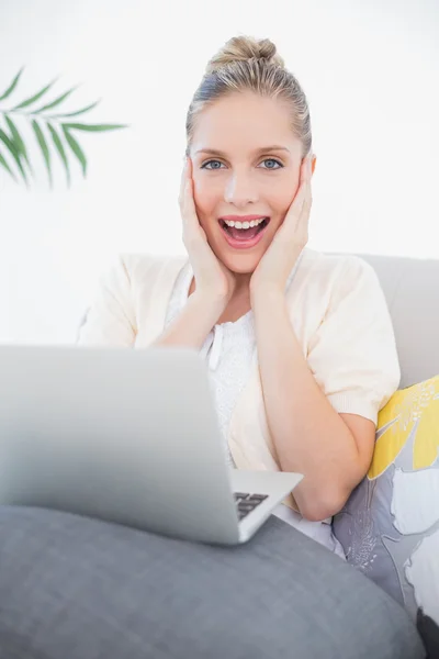 Excited fresh model using laptop sitting on sofa — Stock Photo, Image