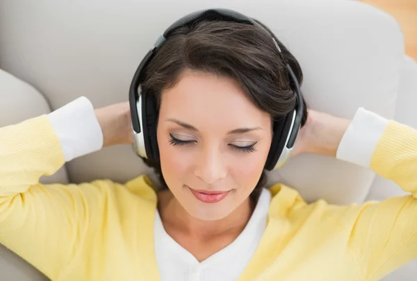 Peaceful casual brunette in yellow cardigan enjoying music — Stock Photo, Image