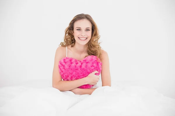 Smiling attractive brunette holding heart pillow — Stock Photo, Image