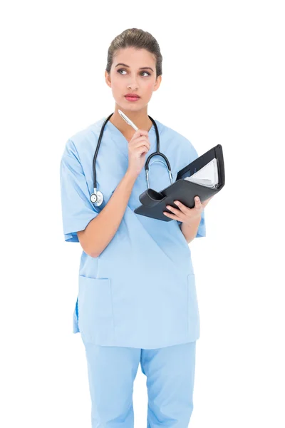 Promyšlené sestra v modrém drhne, drží agendu — Stock fotografie