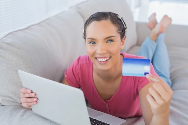 Smiling woman holding laptop showing credit card — Stock Photo, Image