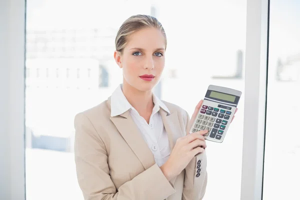 Seriöse blonde Geschäftsfrau zeigt Taschenrechner — Stockfoto