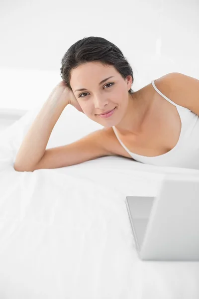 Pleased casual brunette in white pajamas looking at camera — Stock Photo, Image