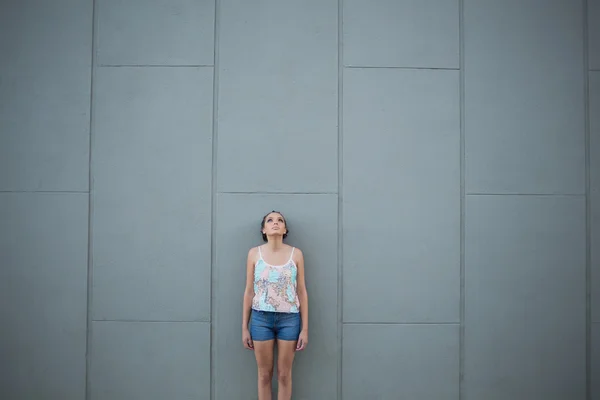 Woman standing in front of grey wall — Stock Photo, Image