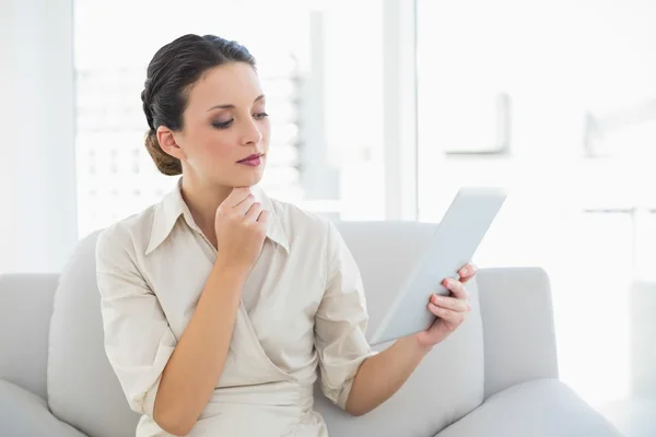 Durchdachte stilvolle brünette Geschäftsfrau mit Blick auf einen Tablet-PC — Stockfoto