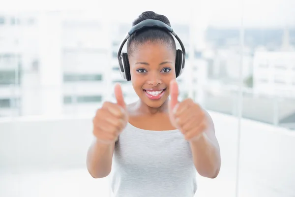 Mujer feliz escuchando música con auriculares y dando pulgares hacia arriba —  Fotos de Stock