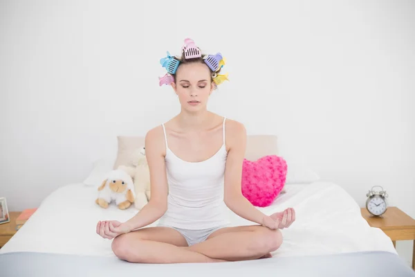 Mujer tranquila en rulos para el cabello practicando yoga — Foto de Stock