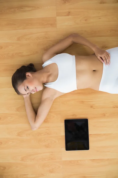 Sporty with closed eyes lying next to a tablet — Stock Photo, Image