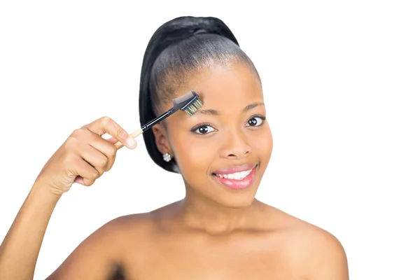 Belle femme se brossant les sourcils et regardant la caméra — Photo