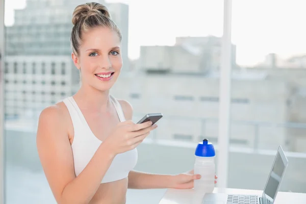 Smiling athletic blonde sending a text — Stock Photo, Image