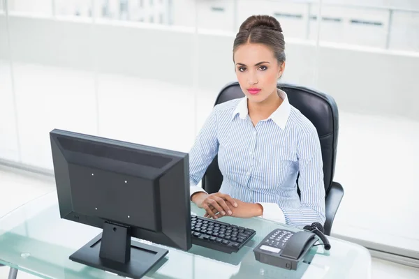 Koncentruje się brunetka kobieta siedzi przy biurku — Zdjęcie stockowe