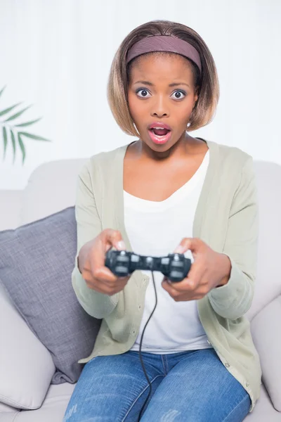 Shocked woman sitting on sofa playing video games — Stock Photo, Image