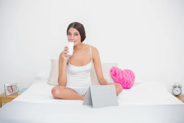 Entspanntes Model im weißen Pyjama, das Milch trinkt — Stockfoto