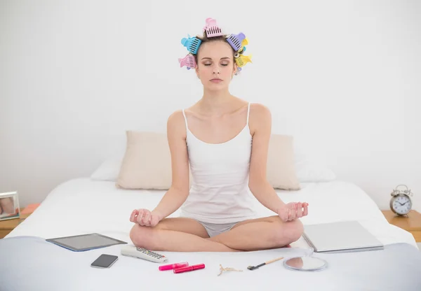 Mujer pacífica en rulos de pelo meditando en posición de loto —  Fotos de Stock