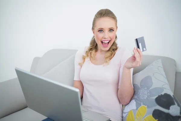 Casual animado loira segurando laptop e cartão de crédito — Fotografia de Stock