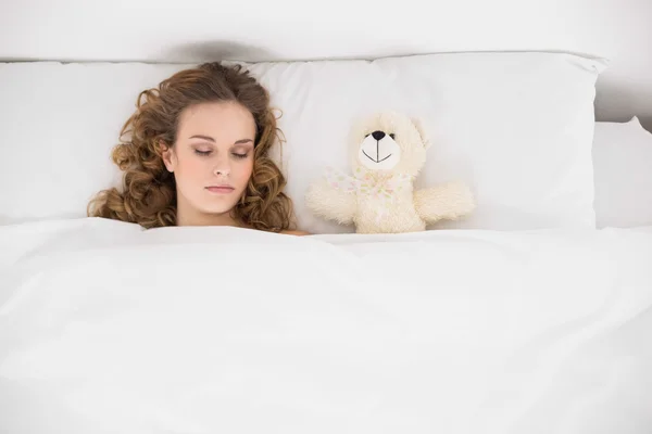 Beautiful brunette sleeping next to teddy bear — Stock Photo, Image