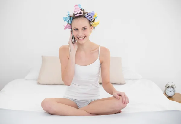 Delighted woman in hair curlers calling with her mobile phone — Stock Photo, Image