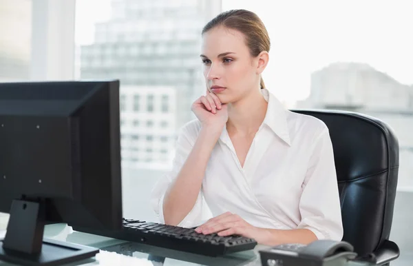 Pensativa mujer de negocios sentada en el escritorio mirando la computadora —  Fotos de Stock