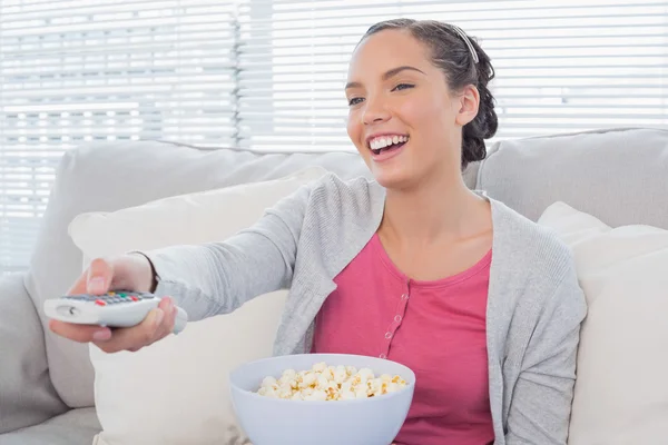 Fröhliche attraktive Frau, die Popcorn isst, während sie fernsieht — Stockfoto