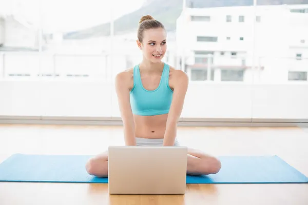 Sportig innehåll kvinna sitter med benen i kors framför laptop — Stockfoto