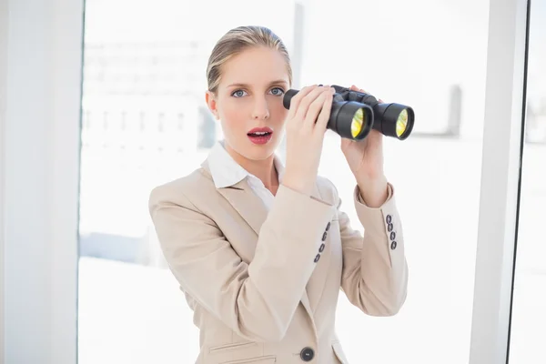 Shocked blonde businesswoman holding binoculars — Stock Photo, Image